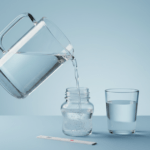 Wasserfilterkanne gießt in Babyfläschchen, Nitrat Teststreifen und Glas als Funktionshinweis im Studio