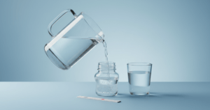 Wasserfilterkanne gießt in Babyfläschchen, Nitrat Teststreifen und Glas als Funktionshinweis im Studio