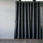 Schallschutzvorhang vor Fenster mit dichtem Teppich im Studio, minimalistisch, weiches Seitenlicht, pastellene Farbwelt und viel Negativraum