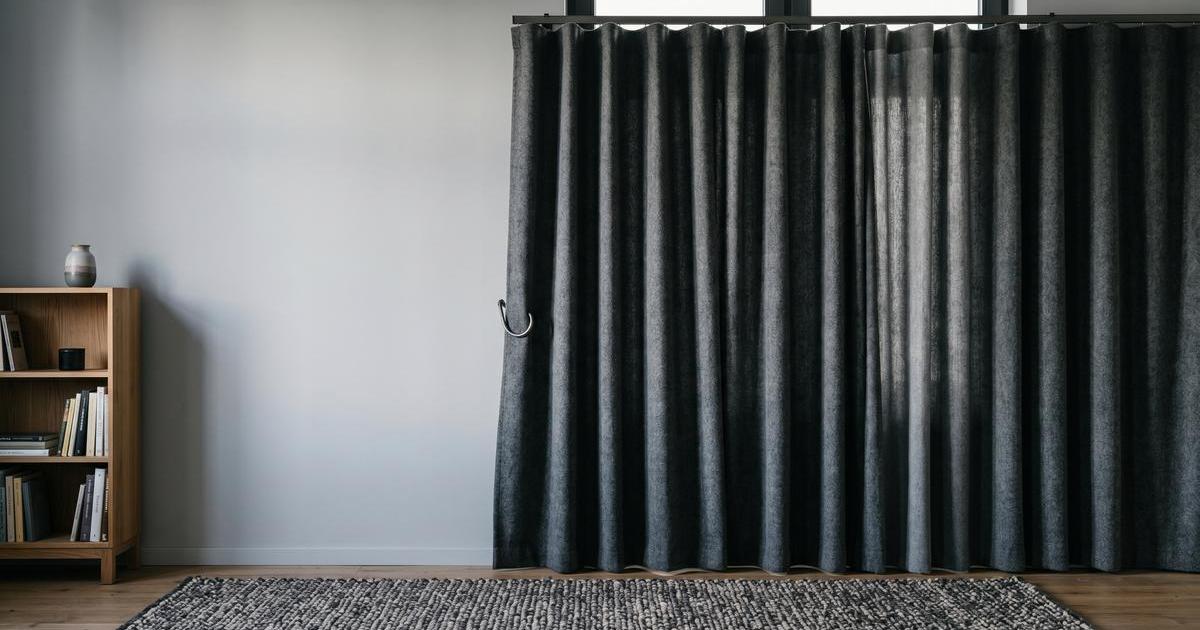 Schallschutzvorhang vor Fenster mit dichtem Teppich im Studio, minimalistisch, weiches Seitenlicht, pastellene Farbwelt und viel Negativraum