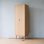 Kleiderschrank mit sichtbarem Wandabstand im Studio, Holzkeile und Luftgitter als Hinweis auf Hinterlüftung