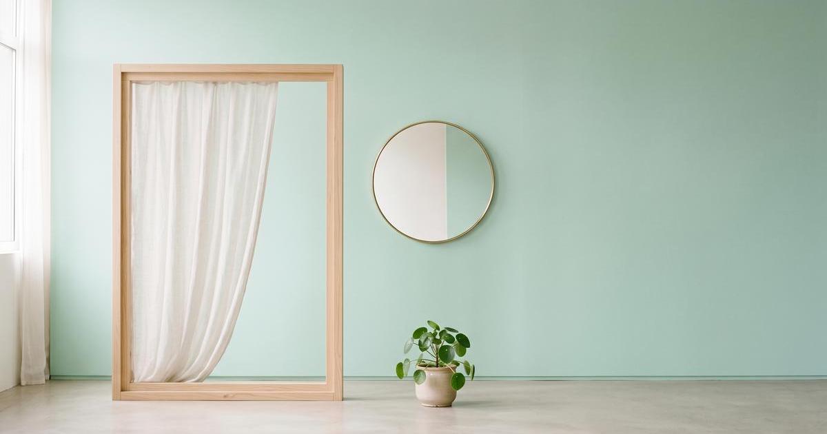 Minimalistisches Stillleben mit Fensterrahmen und halbtransparentem Vorhang, ein Lichtkegel fällt auf pastelligen Hintergrund, Spiegel und Zimmerpflanze als Kontext.